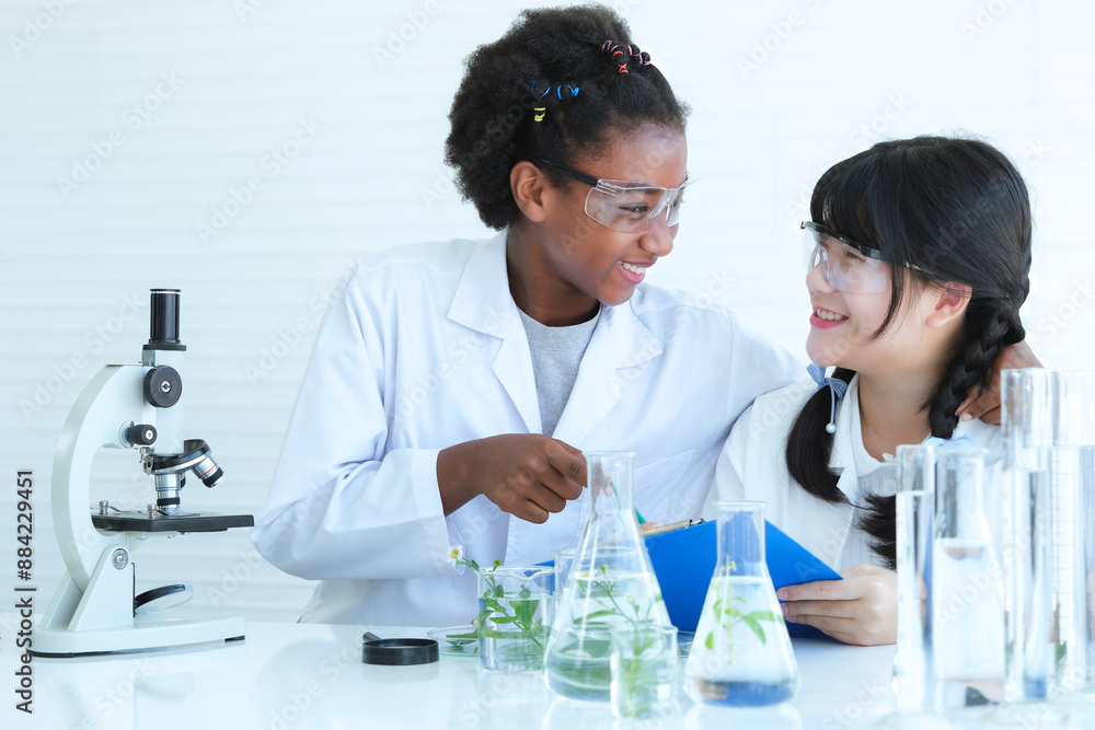 Child scientist with black curly hair and cute girl with glasses holding clipboard happy with the results of successful experiment in the science laboratory. Child scientist with black curly hair and cute girl with glasses holding clipboard happy with the results of successful experiment in the science laboratory.