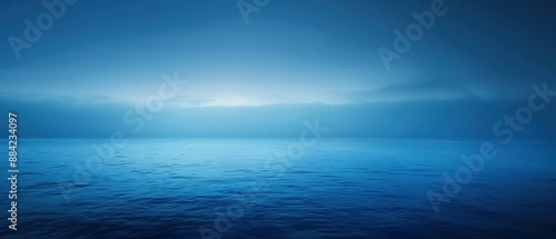 A tranquil blue seascape under a cloudy sky at dawn merging sea and horizon.