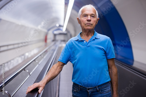 Elderly man standing on moving walkway photo