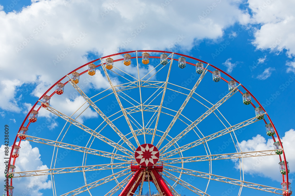 Large modern Ferris wheel against the sky with clouds on a sunny day in an amusement park Large modern Ferris wheel against the sky with clouds on a sunny day in an amusement park