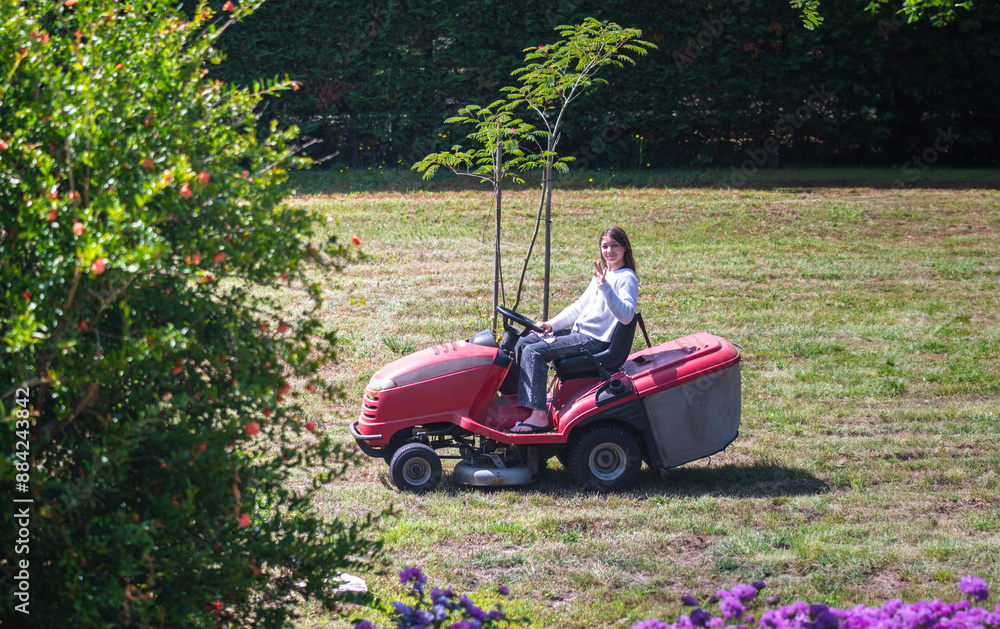 Beautiful young girl enjoying mowing the lawn with a tractor. Beautiful young girl enjoying mowing the lawn with a tractor.