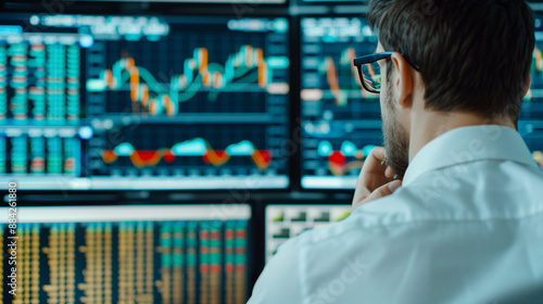 Stock trader looking at stocks and shares on computer in a high rise office