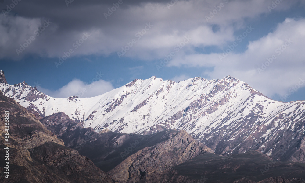 Panorama of mountain range of rocks with snow and glaciers in Pamir in Tajikistan mountains in cloudy weather, minimalistic landscape of high mountains for background Panorama of mountain range of rocks with snow and glaciers in Pamir in Tajikistan mountains in cloudy weather, minimalistic landscape of high mountains for background
