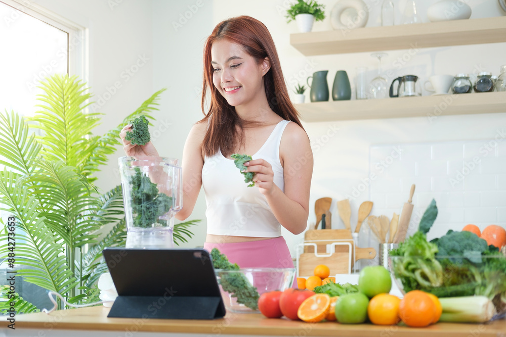 Attractive sporty young woman making vegetable smoothie with blender in kitchen. Healthy lifestyle and dieting concept. Attractive sporty young woman making vegetable smoothie with blender in kitchen. Healthy lifestyle and dieting concept.