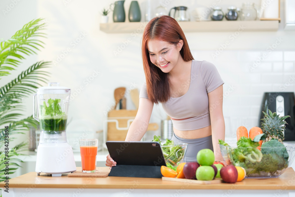 Young sporty woman making healthy vegetables salad while using tablet for looking recipe in the kitchen. Dieting and healthy lifestyle concept. Young sporty woman making healthy vegetables salad while using tablet for looking recipe in the kitchen. Dieting and healthy lifestyle concept.