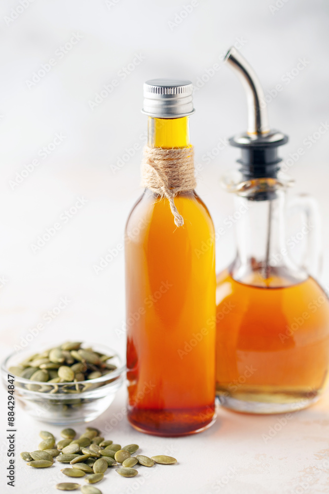 Pumpkin oil and seeds in bottles on a bright background. Pumpkin oil and seeds in bottles on a bright background.