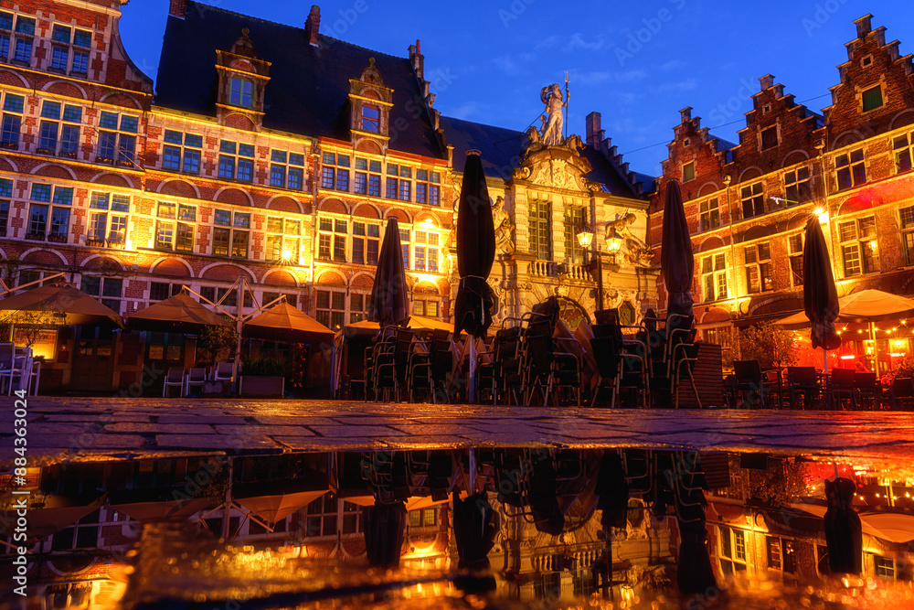 Fototapeta premium Sint Veerleplein medieval square with cafe terraces and old fish market, Ghent, Belgium. Scenic view of historical landmarks, old city architecture at twilight, outdoor travel background