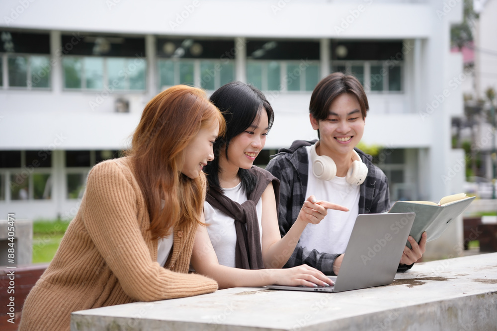 Three young adults happily collaborating on a school project outdoors, using a laptop and a textbook, engaged in a lively discussion, showcasing creativity and innovation Three young adults happily collaborating on a school project outdoors, using a laptop and a textbook, engaged in a lively discussion, showcasing creativity and innovation