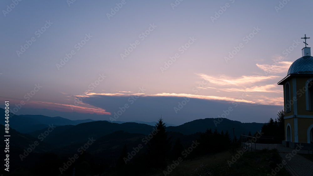 Fototapeta premium Orange sunset with the setting sun behind the mountains