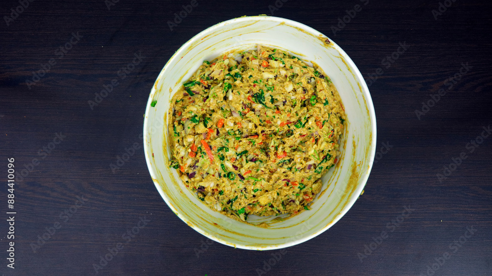 Top View of Mixed Vegetable Pakora Batter in a White Bowl on Dark Wooden Surface - Indian Street Food Preparation Top View of Mixed Vegetable Pakora Batter in a White Bowl on Dark Wooden Surface - Indian Street Food Preparation