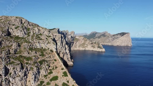 Aerial drone footage of a stunning coastal landscape. The camera glides right, revealing calm blue ocean and towering light-colored cliffs under a clear sunny sky. Perfect for travel and nature projec