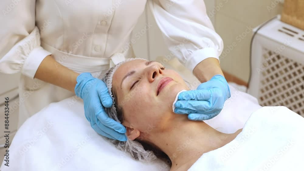 Skin cleansing with cotton pads in the beautician's office. Young woman lies on procedures at the beautician, close up. Skin cleansing with cotton pads in the beautician's office. Young woman lies on procedures at the beautician, close up.