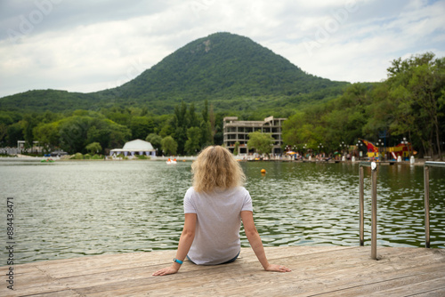 Young woman on beach in Zheleznovodsk, Stavropol Krai, Russia. Girl rests at lake on mountain background. Concept of travel in Zheleznovodsk, summer, nature and resort photo