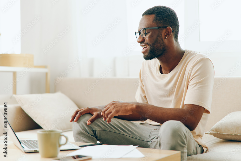Smiling African American Man Working on Laptop in Modern Home Office Smiling African American Man Working on Laptop in Modern Home Office
