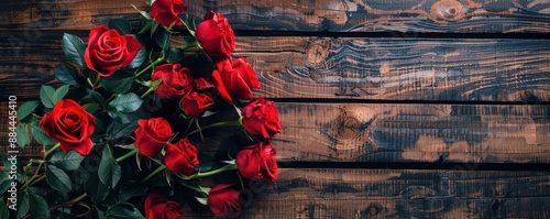 A bouquet of red roses is placed on a wooden table. Free copy space for text. photo