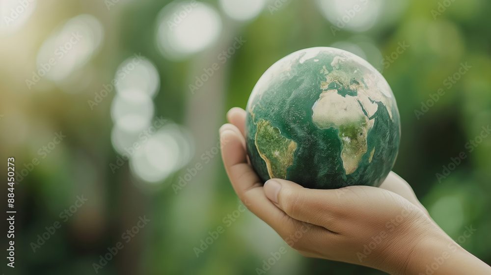 A hand gently holds a small model of Earth against a blurred green background. Emphasizing environmental care and the importance of protecting our planet. A hand gently holds a small model of Earth against a blurred green background. Emphasizing environmental care and the importance of protecting our planet.