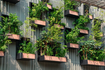 Building facade with green plants growing on balcony. Vertical garden in Kuala Lumpur city, Malaysia. Sustainable modern and ecological architecture
