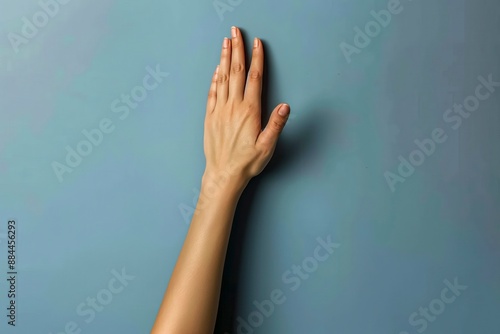 Elegant Hand Pressing Against Blue Background © Greg Kelton