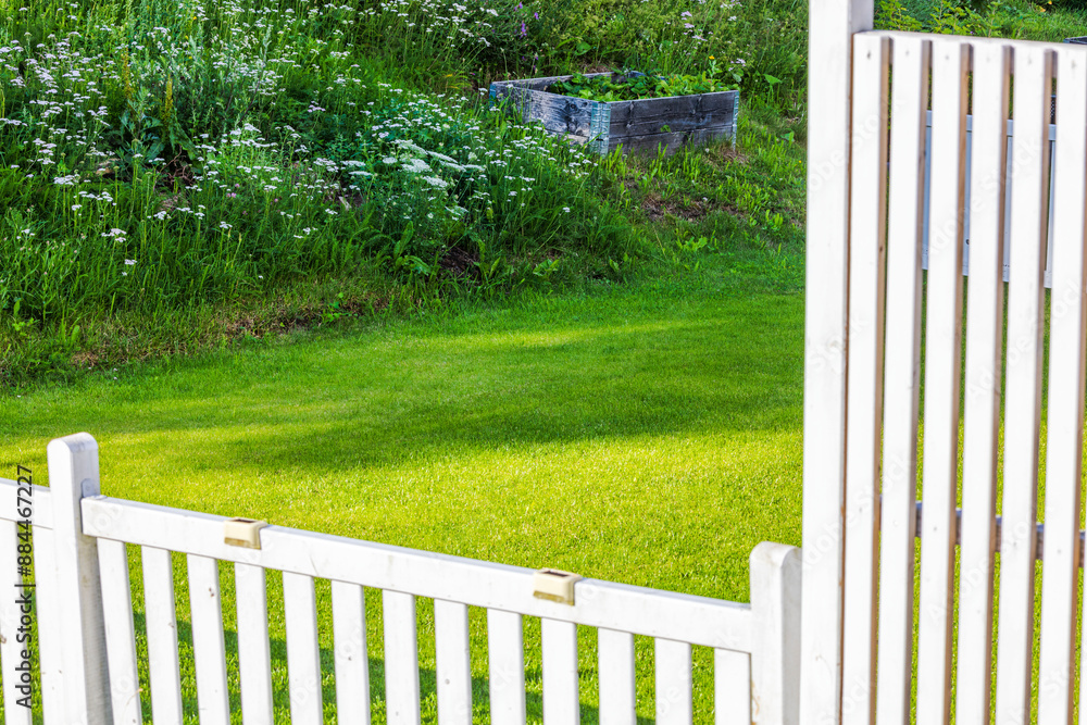 Beautiful view of green lawn in villa enclosed by white wooden fence between neighbors. Sweden. Beautiful view of green lawn in villa enclosed by white wooden fence between neighbors. Sweden.