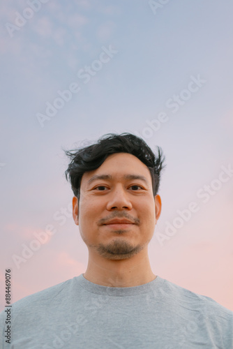 Portrait of asian man standing with smooth colorful sunset sky.