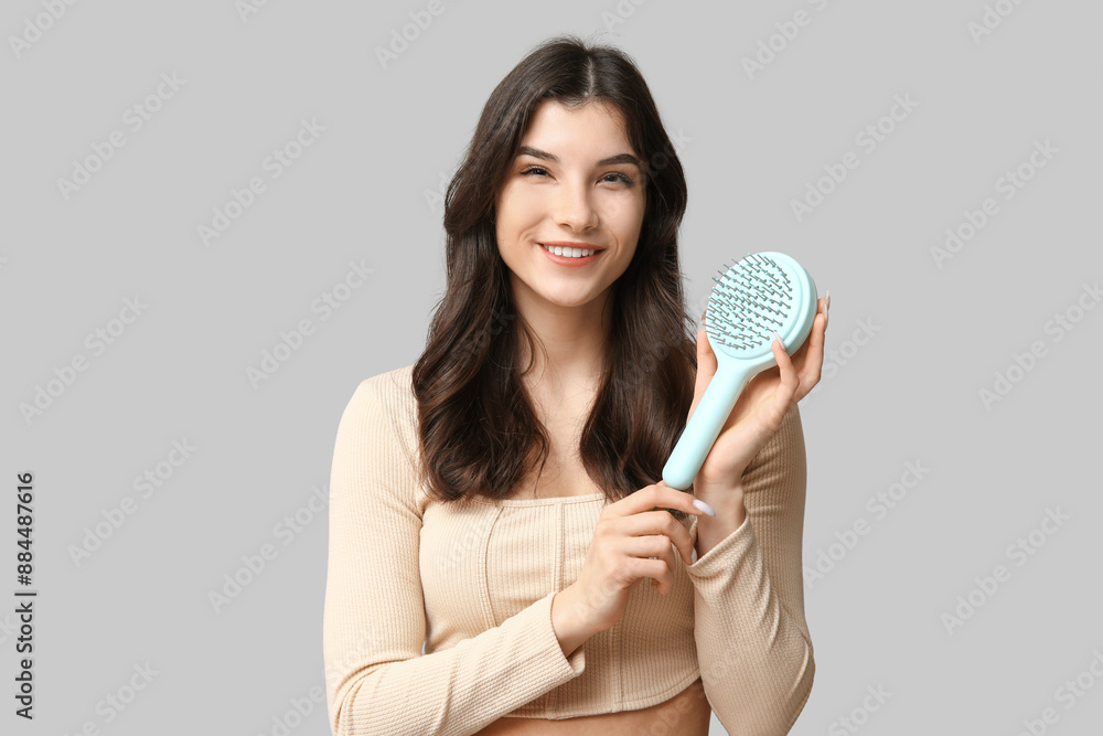 Beautiful young woman with blue hair brush on grey background Beautiful young woman with blue hair brush on grey background
