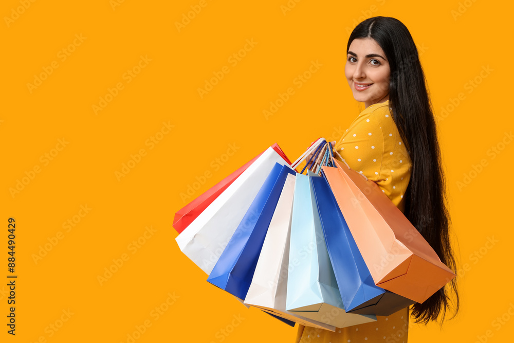 Happy smiling young woman with shopping bags on yellow background Happy smiling young woman with shopping bags on yellow background