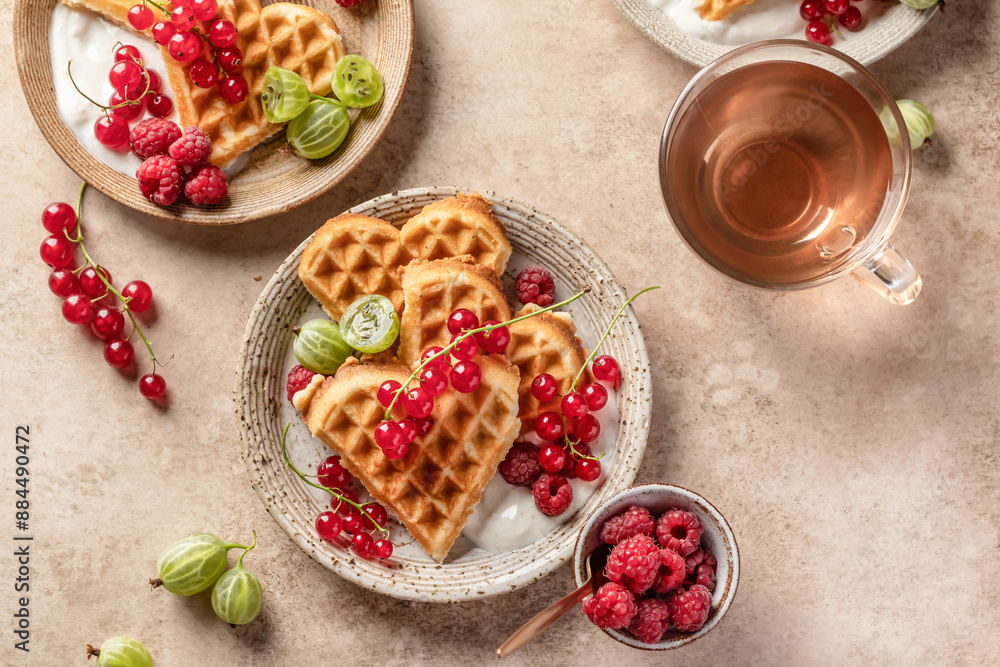 Homemade waffles with summer berries and yogurt served for sweet breakfast with tea on beige background. Heart shaped waffles top view Homemade waffles with summer berries and yogurt served for sweet breakfast with tea on beige background. Heart shaped waffles top view