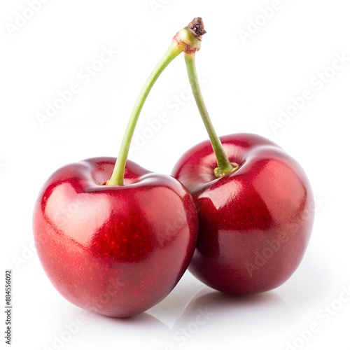 Two ripe cherries with green stems against a white backdrop