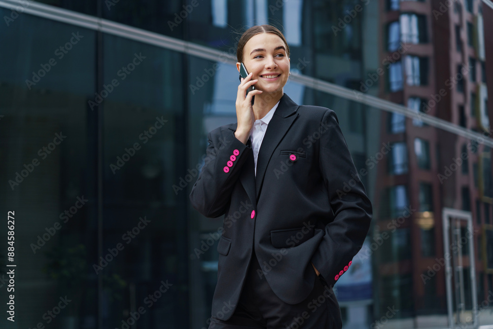 Creative manager woman in a black suit talking on a smartphone in an urban business area. Creative manager woman in a black suit talking on a smartphone in an urban business area.