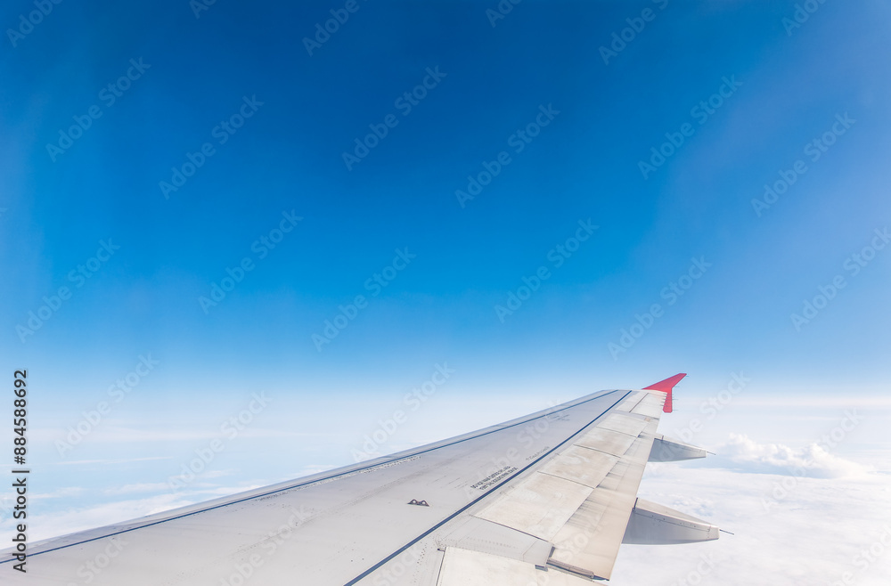 Fototapeta premium View from the airplane window at a beautiful cloudy sky and the airplane wing