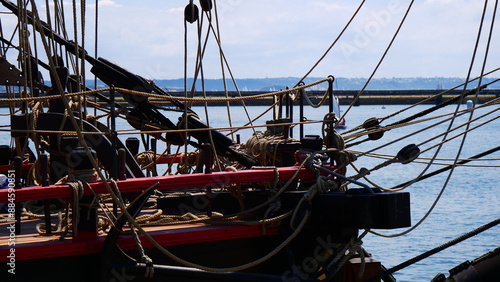 Préparation de sortie de grand bateau à voile ou de gréement, sortie des voiles pliées, rangement de matériel naval, organisation minutieuse, drapeaux flottant sous le vent, festival convial, sortie photo