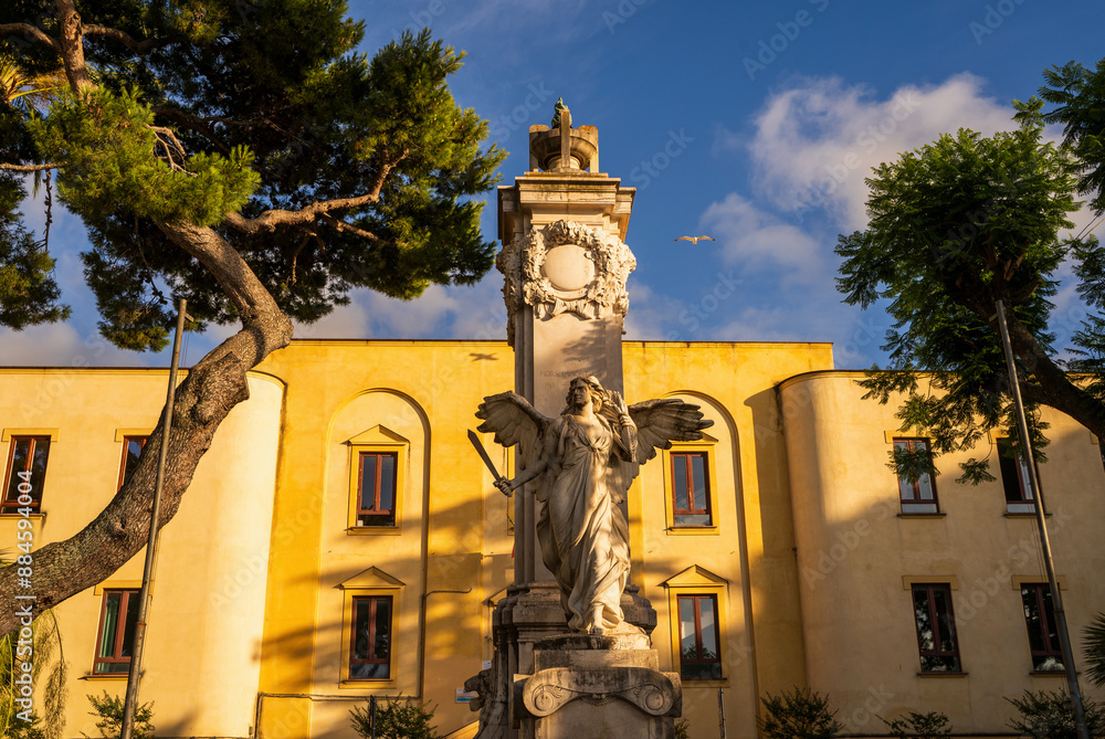 Elegant angel statue in front of a historic building, captured on a sunny day. Mors Immortalis monument, Piazza della Vittoria