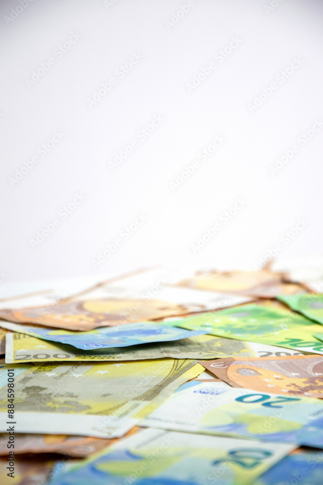 A close-up image of euro banknotes scattered on a white background, with a shallow depth of field and a blurry background A close-up image of euro banknotes scattered on a white background, with a shallow depth of field and a blurry background