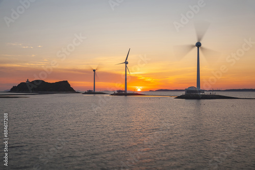 Silhouette and sunset view of three wind generators and Nueseom Island on the sea against glow in the sky at Tando Port near Ansan-si, South Korea 