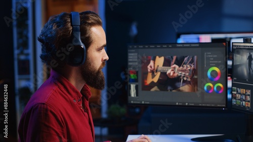 Video editor adds sound effects to filmed footage, working in post production creative studio. Videographer using headphones to test and improve audio quality, editing clips with professional software
