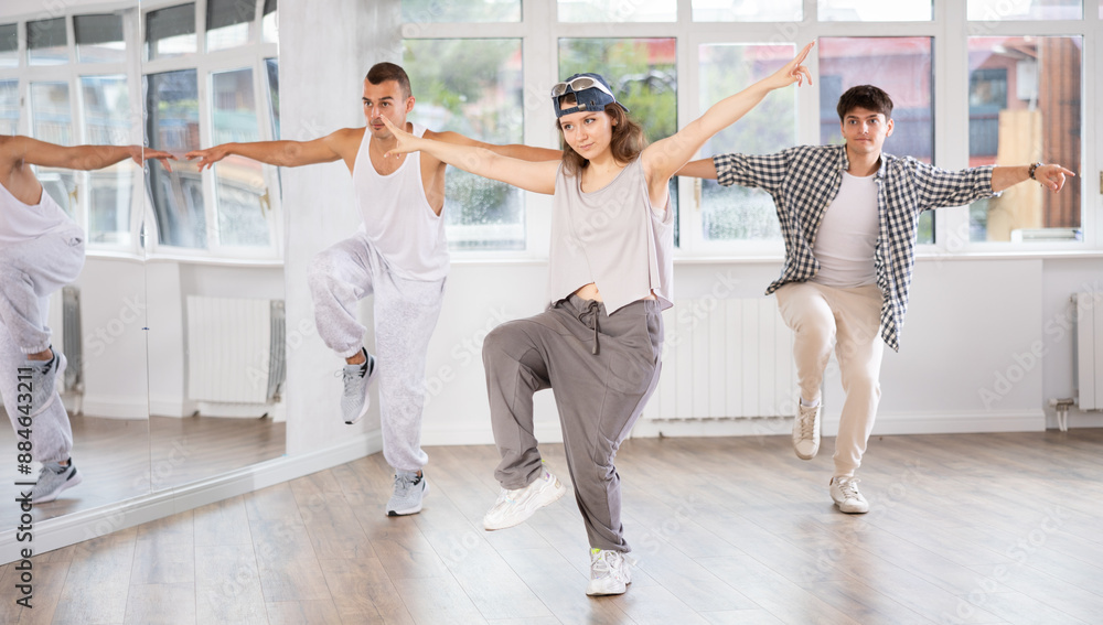 Obraz premium During hip hop dance lesson, girl leads, conducts classes, teaches students to correctly perform elements and sequence of movements and moonwalk