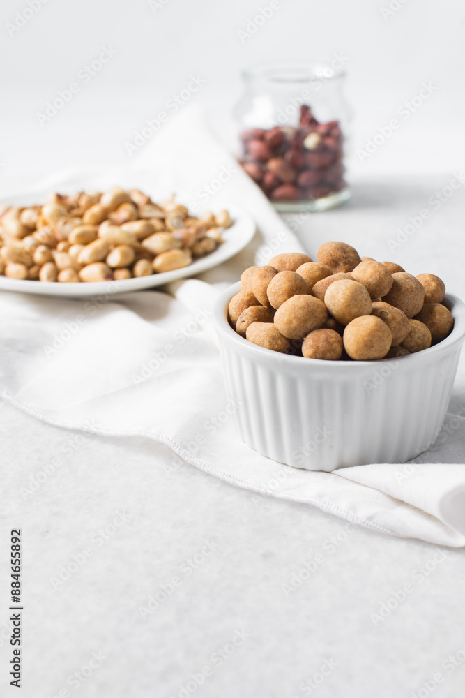Fried coated peanuts in a white ceramic ramekin, cracker peanuts on a marble countertop, nigerian peanut snack in a small white bowl Fried coated peanuts in a white ceramic ramekin, cracker peanuts on a marble countertop, nigerian peanut snack in a small white bowl