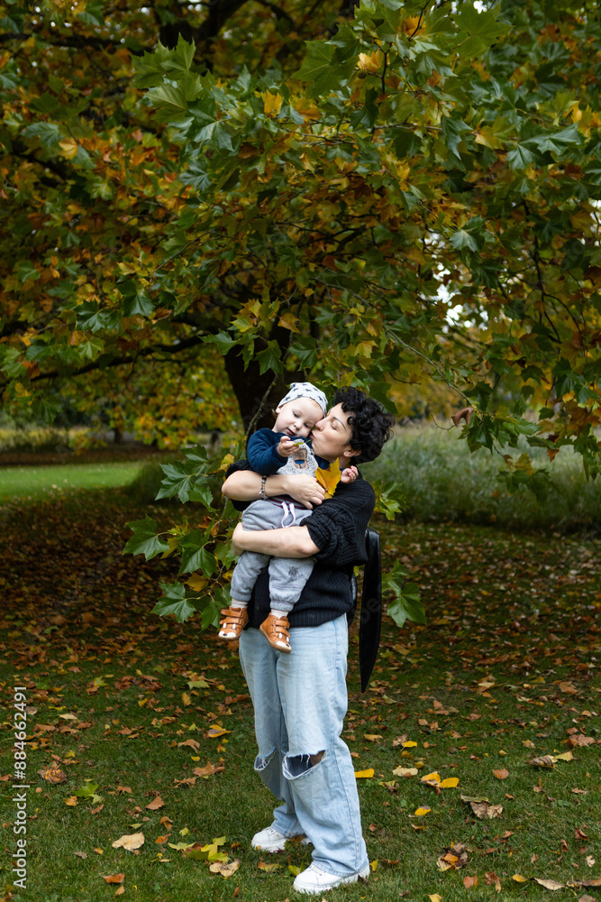 Fototapeta premium Young mother and her little son having fun in the autumn park.