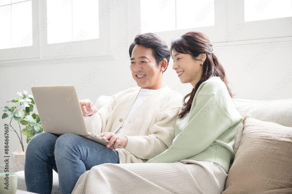 Smiling middle-aged couple in their 50s searching for a computer to look at Smiling middle-aged couple in their 50s searching for a computer to look at