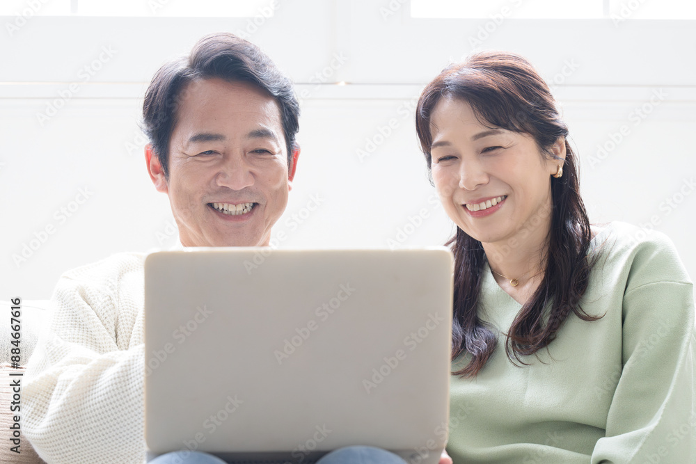 Smiling middle-aged couple in their 50s looking at computer looking for search Front close-up Smiling middle-aged couple in their 50s looking at computer looking for search Front close-up
