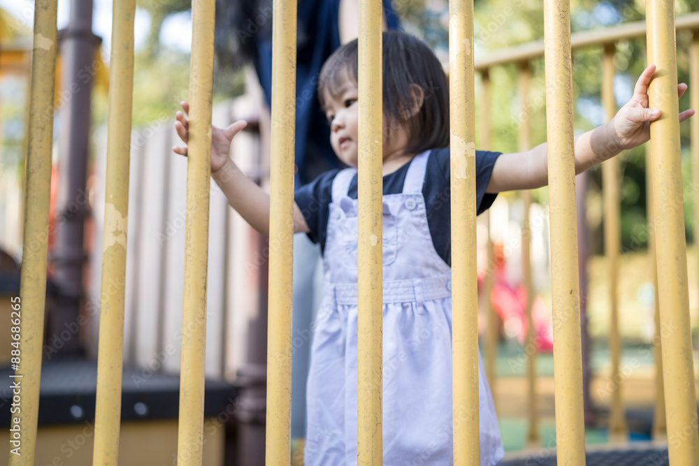 Obraz premium A one-year-old Chinese Malaysian girl playing on the children's playground equipment with her thirty-something mother at KLCC Park in Kuala Lumpur City Centre, Malaysia.