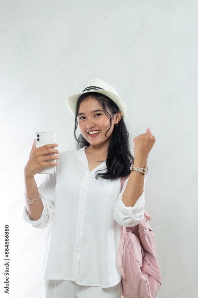 Beautiful young Asian woman tourist in pink straw hat excited and showing smart phone buying tickets online, holiday travel advertising, isolated white background Beautiful young Asian woman tourist in pink straw hat excited and showing smart phone buying tickets online, holiday travel advertising, isolated white background