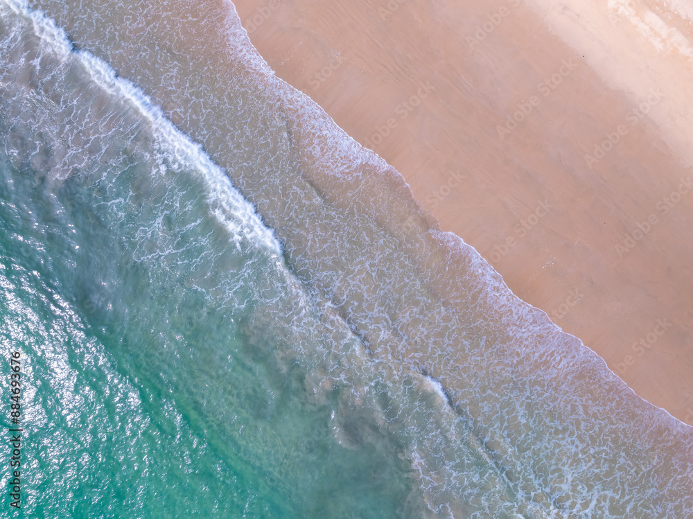 Fototapeta premium Aerial top view nature background of waves crashing in the ocean sea water, Drone view of sea waves in bird eye view photo,Beach sea background