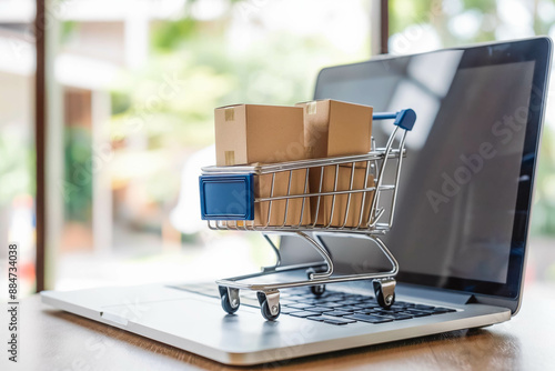 Online shopping concept with cart full of boxes on top of laptop computer