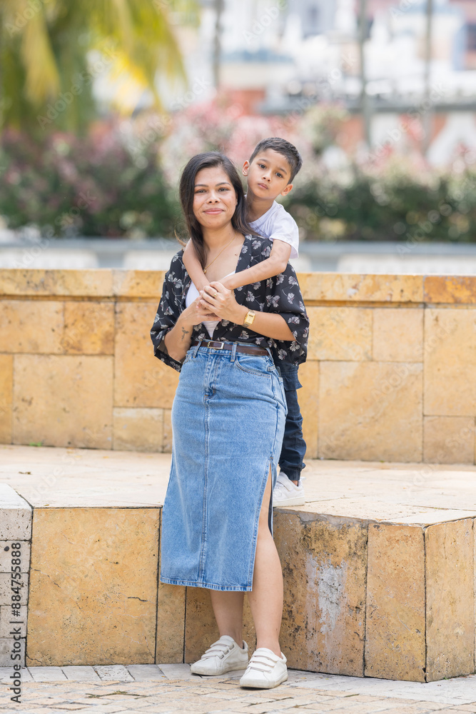 A 30-something Indian Malaysian mother in a denim skirt and her 7-year-old son in a white T-shirt spending time joyfully in a historic cobblestone park in City Centre, Kuala Lumpur, Malaysia. A 30-something Indian Malaysian mother in a denim skirt and her 7-year-old son in a white T-shirt spending time joyfully in a historic cobblestone park in City Centre, Kuala Lumpur, Malaysia.