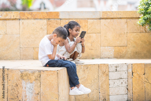 A 30-something Indian Malaysian mother in a denim skirt and her 7-year-old son in a white T-shirt spending time joyfully in a historic cobblestone park in City Centre, Kuala Lumpur, Malaysia.