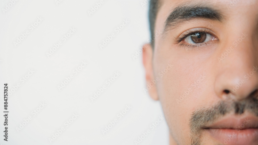 Fototapeta premium Sight correction. Vision medicine. Ophthalmology clinic. Calm man half face portrait with healthy brown iris eye isolated on white background empty space.