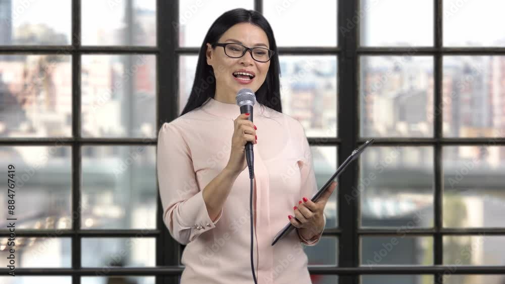 Portrait of beautiful asian woman in sunglasses singing giving a speech with microphone. Checkered indoor window in the background. Portrait of beautiful asian woman in sunglasses singing giving a speech with microphone. Checkered indoor window in the background.