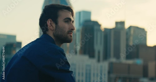 Young man standing on a bridge looking out at the sunset