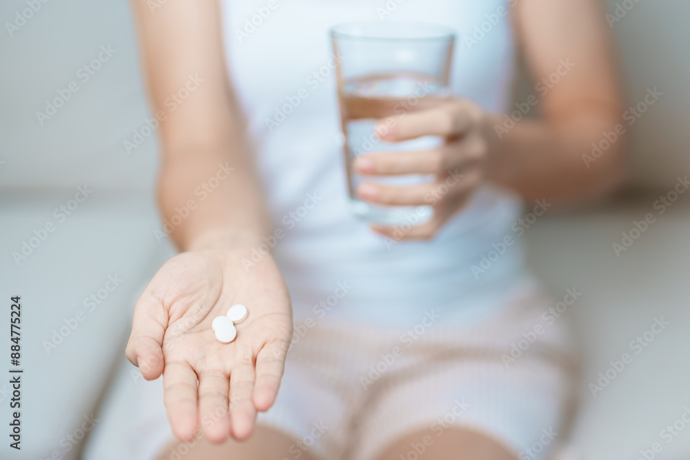 woman hand holding medicine painkiller pill and water glass on the sofa at home, taking for headaches, stomach ache, Diarrhea Pain from food poisoning, Endometriosis, Hysterectomy and Menstrual woman hand holding medicine painkiller pill and water glass on the sofa at home, taking for headaches, stomach ache, Diarrhea Pain from food poisoning, Endometriosis, Hysterectomy and Menstrual